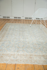 Distressed Oushak rug border with muted floral motifs in slate blue and antique ivory.