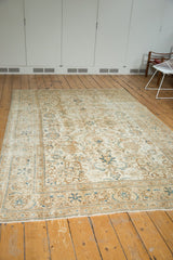 Distressed vintage Sparta carpet corner, featuring ivory, pale gold, and soft blue floral motifs.