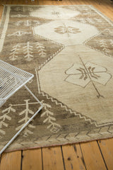 Distressed Oushak corner, low pile with knot heads, primitive plant motifs, beige and brown tones.