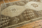 Distressed Oushak rug's low pile with primitive brown and ivory stylized plant motifs.