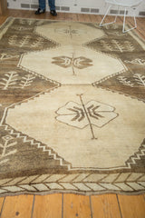 Lower border of distressed vintage Oushak rug with antique ivory and brown leaf motifs.