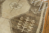 Distressed vintage Oushak carpet with antique ivory plant motifs and zigzag border.