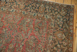 Distressed Arak carpet corner with red floral field and dark ornamental border.