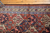 Persian Baktiari rug's low pile border with brick red, indigo, ivory, and blush patterns.