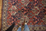 Vintage Baktiari rug with brick red and indigo blue lattice pattern, blossomed plants.