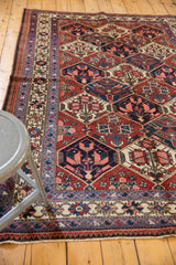 Vintage Baktiari rug corner showing indigo blue border, floral patterns, and brick red field.