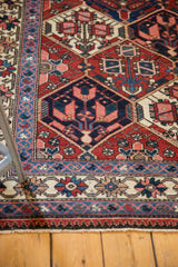 Vintage Baktiari rug detail: brick red lattice, indigo blossomed plant motifs, ivory floral border.