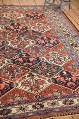 Vintage Baktiari rug's brick red lattice field, blossomed plants, and ivory floral border.