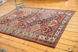 Corner view of vintage Baktiari rug, highlighting intricate border and red-blue floral lattice design.