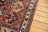 Ornate ivory floral border and geometric field details on the vintage Baktiari rug.