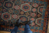 Detailed view of vintage Kurdish rug's geometric guls in mallard green, indigo, blush.