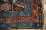 Kurdish rug corner: geometric guls in sky blue, red, charcoal; worn pile, secured side.