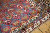 Hand-knotted antique Persian rug with raspberry red field, blue lattice, and germinating plant motifs.