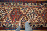 A standing perspective over an antique Serab runner, showing the texture of repeating geometric medallions.