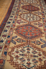 A close, angled view of the low-pile texture and repeating hooked medallions on an antique Serab runner.
