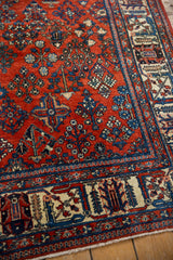 Distressed Joshegan carpet detail: black cherry red field, sapphire blue garden motifs.