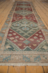 Distressed antique Malayer runner with unique geometric medallion, featuring sea foam green, wine red, and ivory.