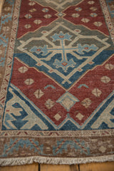 Distressed texture of the Malayer runner's border and fringe, showcasing red, blue, and sand tones.