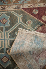 Distressed Malayer runner's hand-knotted foundation, fringe, and seafoam green, wine red pile.