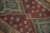 Distressed Malayer runner's worn pile, revealing wine red, green, and ivory geometric patterns.