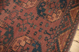 Patinaed red-rust Ersari field with dark navy and chestnut motifs, zigzag border.