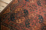 Vintage Ersari carpet detail with repeating geometric floral medallion, red rust, navy blue, and even wear.