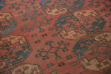 Vintage Ersari carpet detail showing time-softened rust-red pile and mallard green floral motifs.