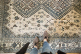 Distressed vintage Shiraz rug detail, displaying soft blue, beige, and geometric plant motifs.