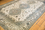 Distressed vintage Persian Shiraz carpet showing geometric patterns in muted blue and beige.