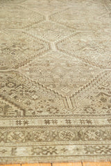 Distressed vintage Shiraz carpet's worn pile, featuring muted geometric patterns.