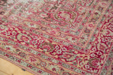 Distressed vintage Meshed rug corner, raspberry red floral borders with visible wear.