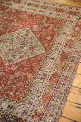 Distressed reddish-brown Qashqai carpet border with intricate light blue and ivory motifs.