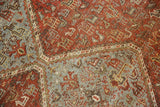 Distressed vintage Qashqai carpet's tribal motifs and interconnected diamond contour in soft tones.