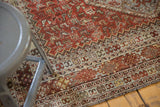 Detail of distressed Qashqai rug with worn pile, faint foundation, rustic red, and geometric patterns.