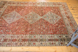 Distressed vintage Qashqai carpet displaying faded field colors and geometric tribal motifs.