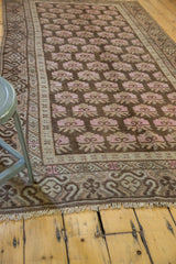 Distressed vintage Khotan rug corner, faded pink floral motifs, undulating border, fringe.