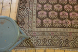 Distressed vintage Khotan rug features faded pink floral bouquets, European-influenced undulating borders.