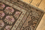 Khotan rug corner with distressed pink floral bouquets and undulating brown border.