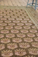 Distressed Khotan rug pile with faded pink floral bouquets and Khotan-style undulating border.