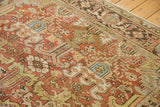 Textured brick red and celadon green geometric patterns on a distressed vintage Heriz carpet.