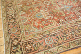 Textured vintage Heriz rug corner displaying faded brick red and powder blue motifs.