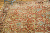 Distressed vintage Heriz rug detail: geometric patterns in dusty brick red, powder blue, and celadon green.