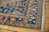 Hand knotted Khotan carpet, showing navy field, beige border, dusty tangerine motifs, and secured fringe.