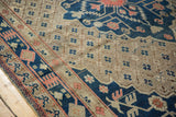 Vintage Khotan carpet with a navy blue geometric border and beige field with delicate trellis design.