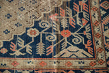 Vintage Khotan rug detail showing dusty tangerine border motifs and navy trellis field.