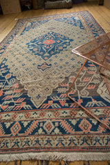 Vintage Khotan carpet, navy blue elongated medallion, orange trefoil, and faded ivory trellis.