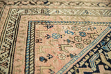 Intricate sky blue and navy geometric patterns on the blush ground of a vintage Hamadan rug.