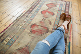 Worn red geometric medallions, low pile, and intricate borders on this Caucasian runner.