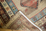 Antique Caucasian rug runner, folded to reveal worn low pile, foundation, and geometric borders.