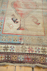 Frayed fringe and geometric borders on antique Caucasian runner end, with red, blue, and ivory tones.